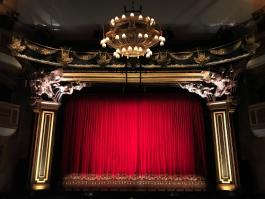 Ornate theater stage with closed red curtains