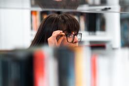 woman with glasses looking at bookshelves