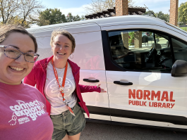two staff standing in front of the library van