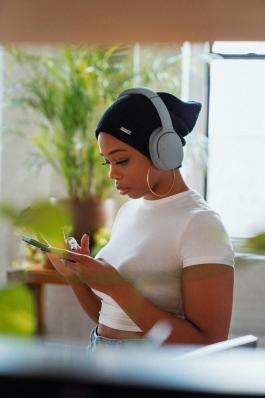 Photo of a woman with headphones looking at her cell phone
